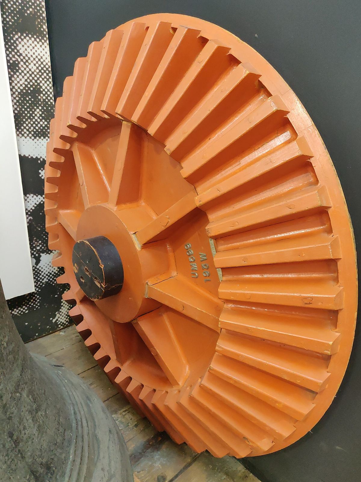 Een houten gietmodel voor een kegeltandwiel, oranje gelakt, met de tanden en de naaf in hout uitgewerkt.